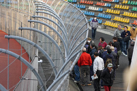 フェンスの手前に落下したサイン帽子と金網に集まる観客