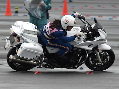 大型バイクHONDA CB1300に乗り長い後ろ髪をなびかせて走る女性白バイ隊員
