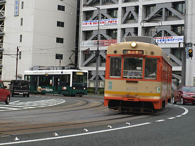 松山市街地の道路を走る伊予鉄道のオレンジ色の路面電車モハ2000形