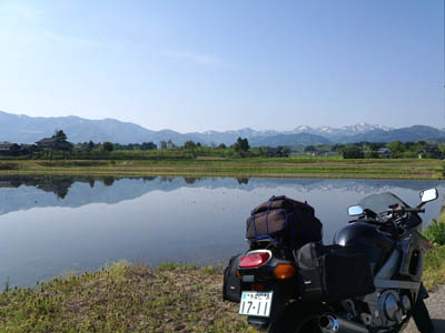 田植え前の水田に映る山とバイク