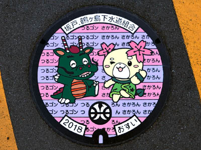 坂戸市のイメージキャラクターである桜の妖精「さかろん」と鶴ヶ島市のイメージキャラクターである幸せを呼ぶ龍「つるゴン」が描かれたデザインマンホール（カラーマンホール）