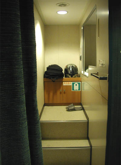 名門大洋フェリー「ふくおか２」の二等洋室（ツーリスト）の二段ベッドへ続く通路の階段と荷物置き場