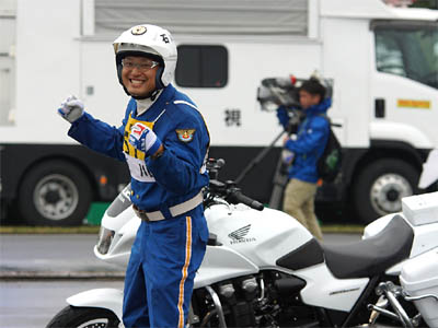 満面の笑顔で観客席の声援に応える石川県代表の白バイ隊員