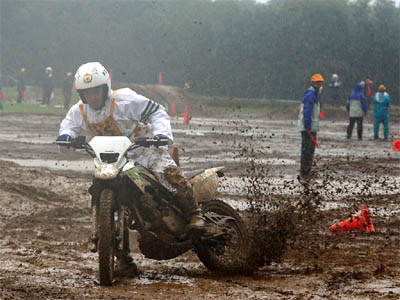 リアタイヤで泥を跳ね飛ばしながらカーブを曲がる神奈川県代表の白バイ隊員とオフロードバイク