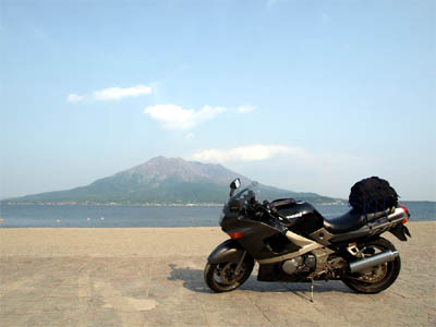 鹿児島の磯海岸の砂浜に停めたバイクと桜島