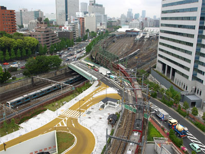 国道15号線の八山橋交差点と陸橋の下を走行するJRの京浜東北線、遠くに見える品川駅と京浜急行の踏切