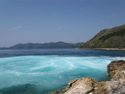 田沢湖発電所の水路から放流された水により鮮やかなエメラルドブルーの湖面が広がる田沢湖