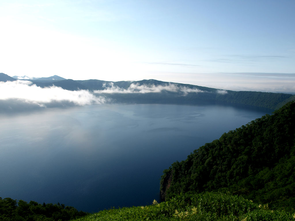 霧が晴れて鮮やかな青色の湖面に広がる摩周湖