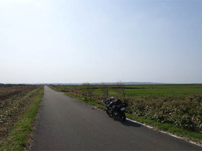 下サロベツ原野の中を通り抜ける細い道路とツーリング中のバイク