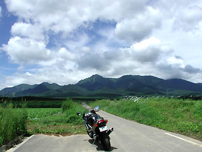 夏の雲が広がる野辺山高原とツーリング中のバイク