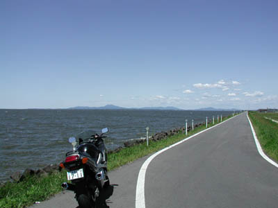 霞ヶ浦の湖畔に沿って走る道路とバイク